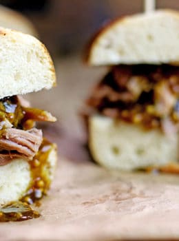 Tender Pulled Pork covered in a homemade raspberry honey mustard sauce with whole mustard seeds served in a toasted pretzel roll. Perfect for your tailgate or gameday party.