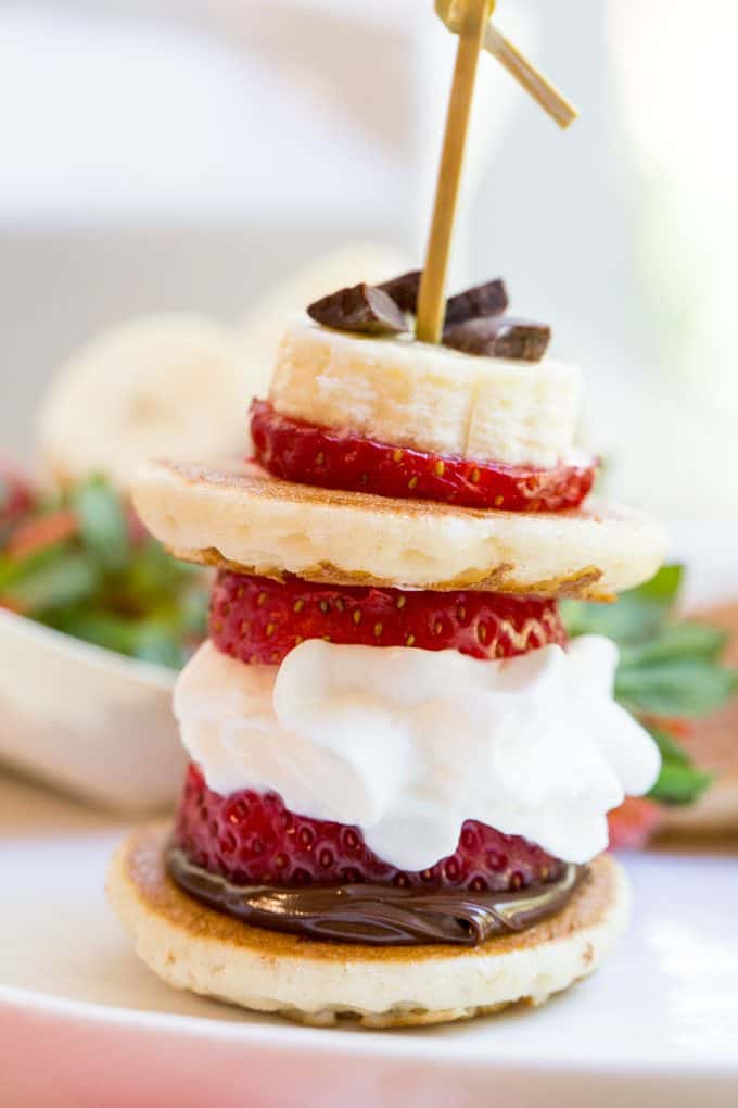 Banana Split Pancake Bites are an easy brunch dish for a party or for your little ones with homemade silver dollar pancakes, Nutella, bananas, strawberries, whipped cream and chocolate chips.