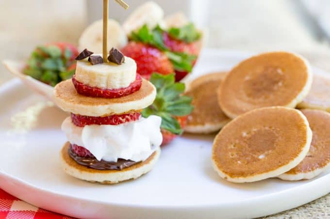 Banana Split Pancake Bites are an easy brunch dish for a party or for your little ones with homemade silver dollar pancakes, Nutella, bananas, strawberries, whipped cream and chocolate chips.
