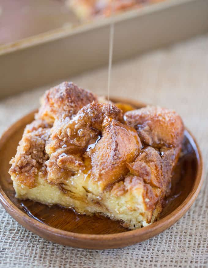 Easy French Toast Bake slice on plate with syrup being drizzled.