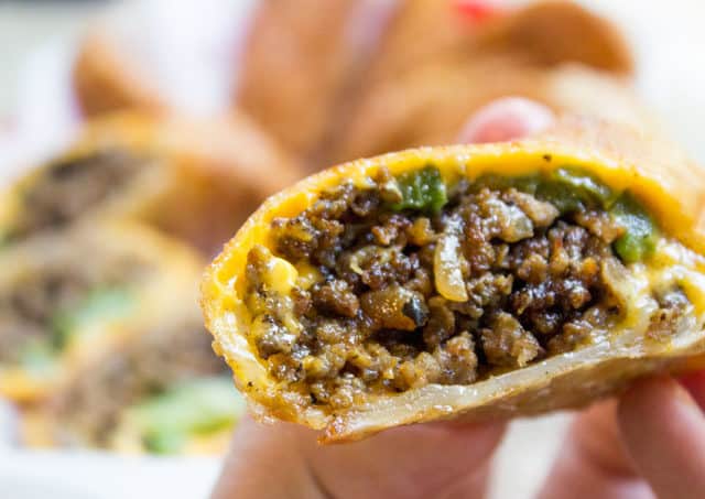 hand holding sliced Cheesesteak Egg Rolls