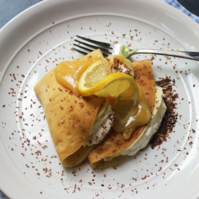 Plated crepes with lemon curd on top.