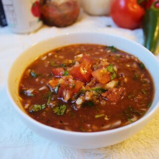 Bowl of prepared salsa with ingredients in background