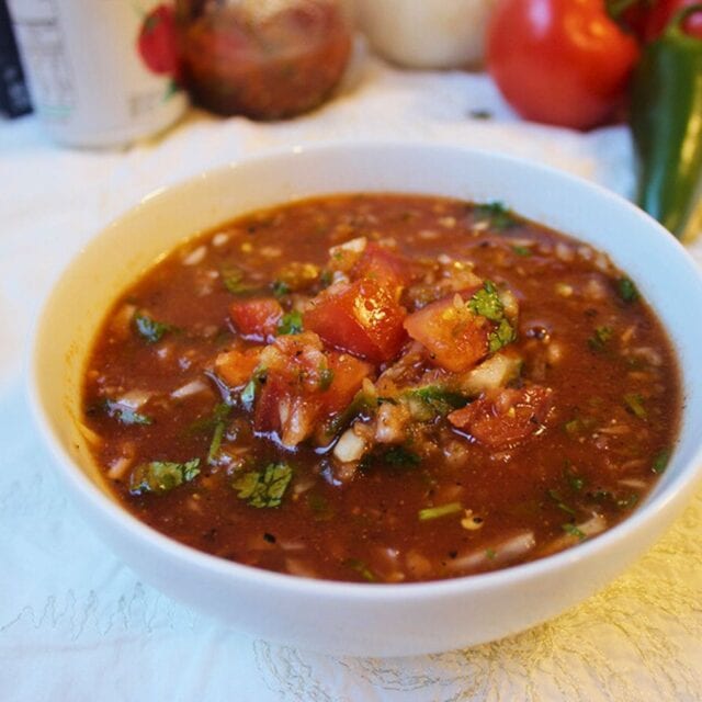 Bowl of prepared salsa with ingredients in background