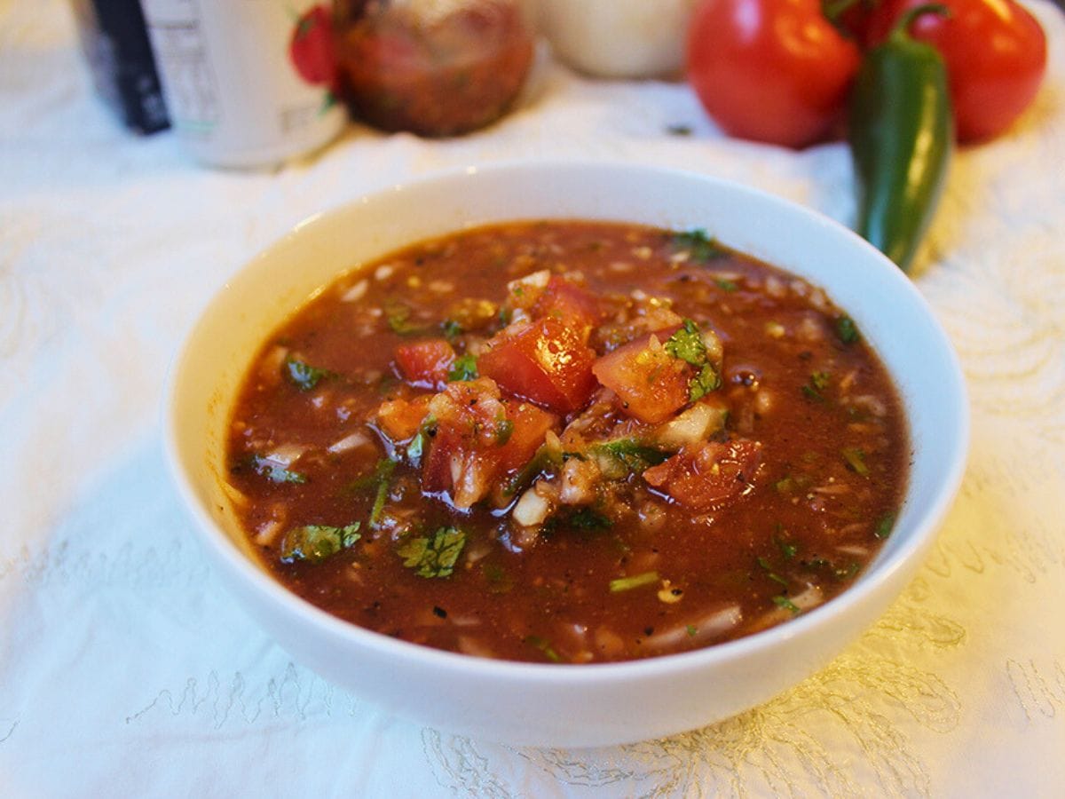 Bowl of prepared salsa with ingredients in background