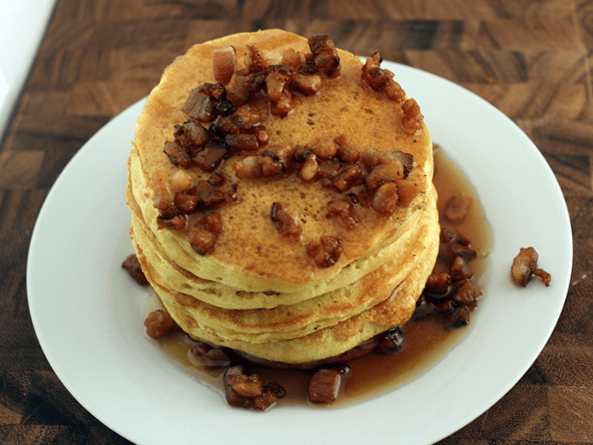 top view of pancake stack with bacon bits and syrup
