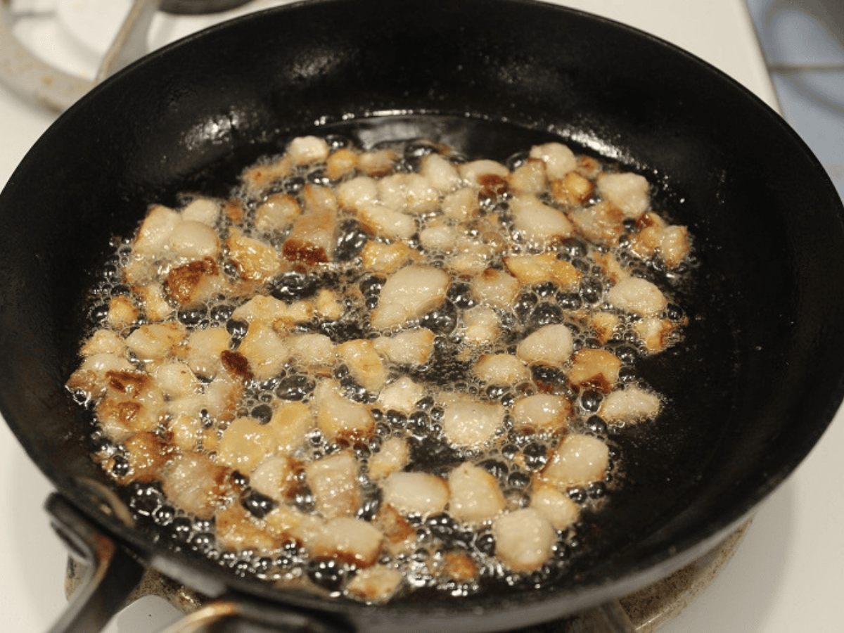 bacon bits cooking in a pan
