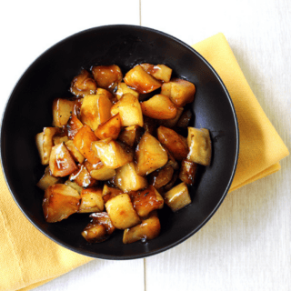 roasted apples in a black bowl on top of yellow napkin