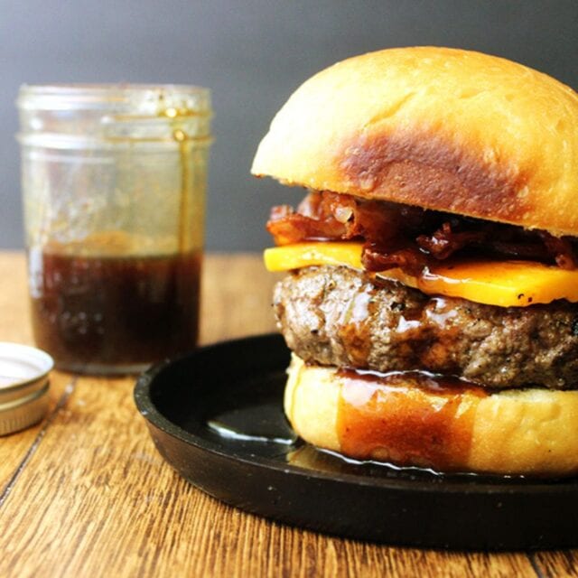 burger on a plate with sauce in a jar behind it