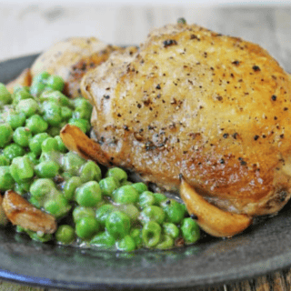 chicken on a plate with creamy peas on side