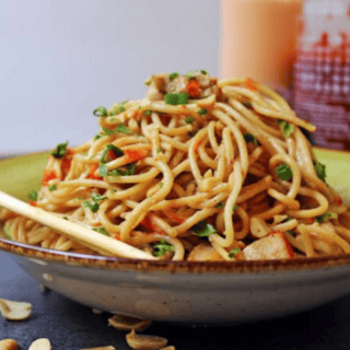 Noodles served in bowl with siracha in background
