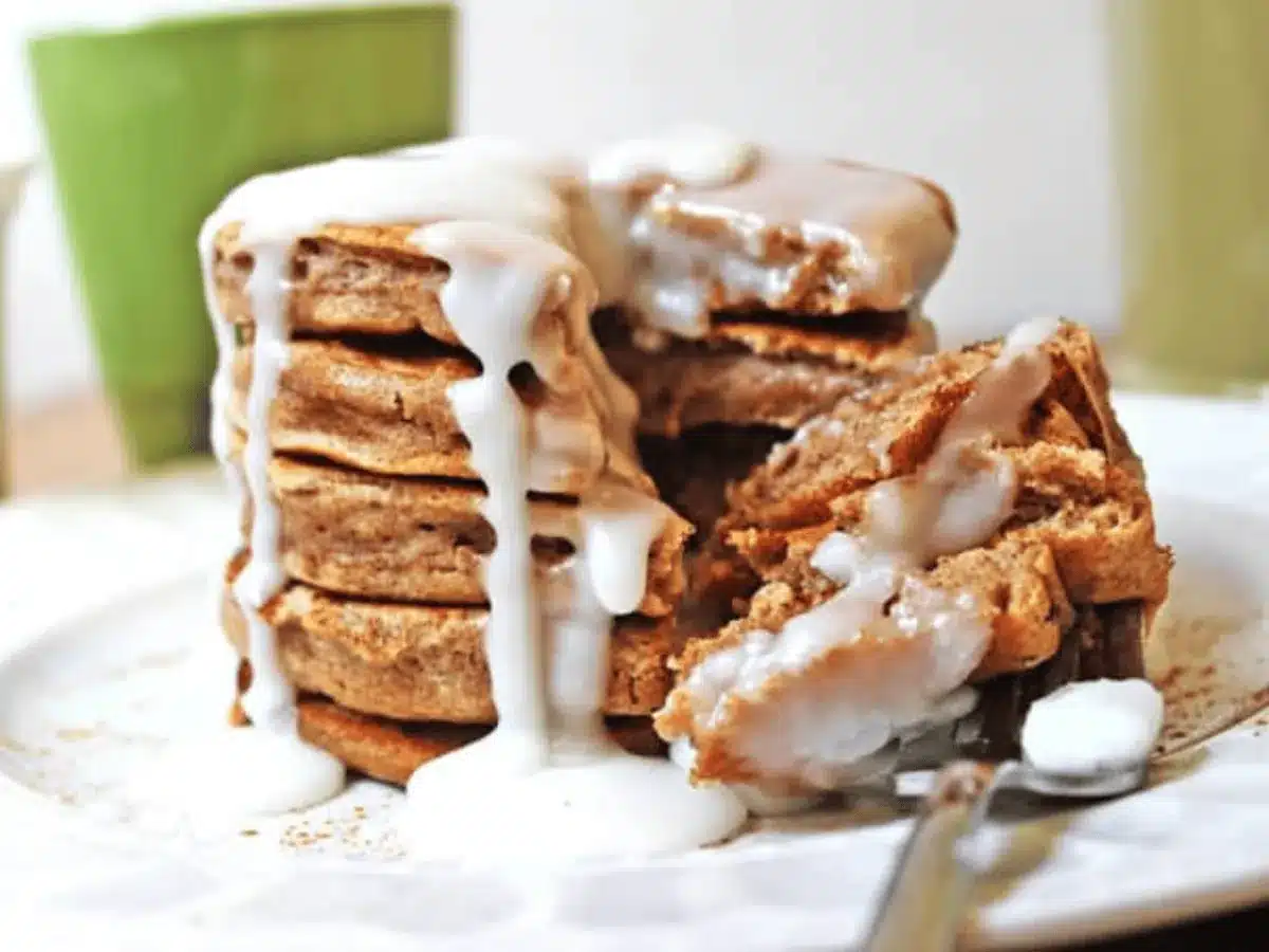 stack of pancakes with icing on a white plate with a fork