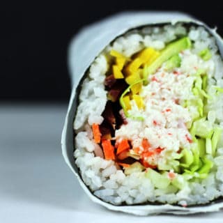 California roll burrito wrapped in seaweed, filled with sushi ingredients.