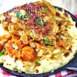 Chicken thighs on top of mashed potatoes with carrots