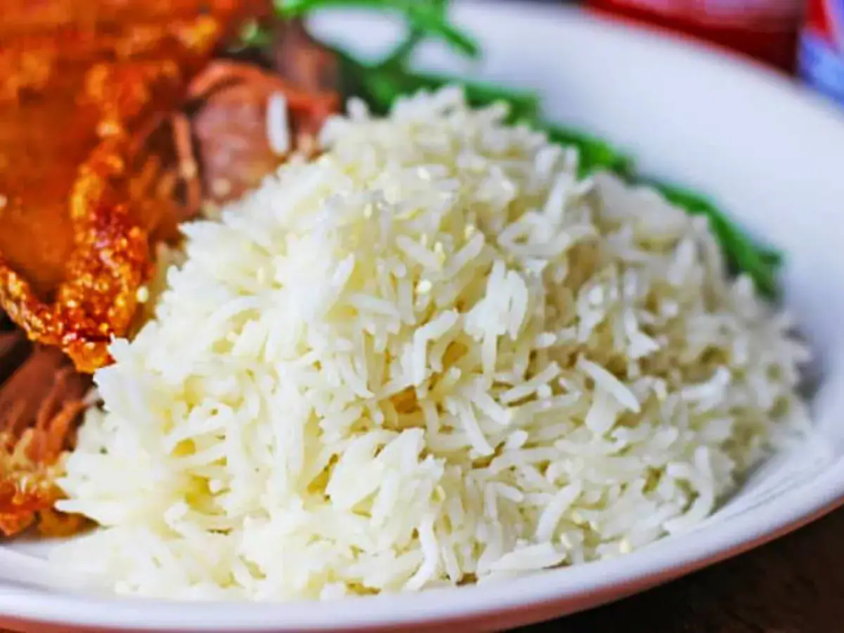 Pile of rice on plate with food in background