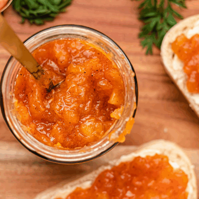 sweet spread in a jar with knife next to two pieces of bread