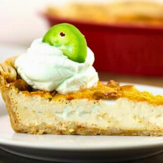 Slice of quiche on a white plate with cream and a pepper slice on top