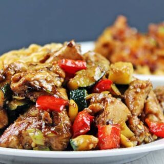 plated chicken and veggies with chow mein in back of plate.