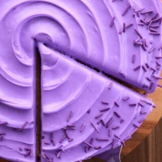 Boxed Cake Mix Hack swaps a few ingredients to make a dense and buttery, rich, bakery style cake that tastes like you paid $6 a slice! purple frosting on cake, top view with slice