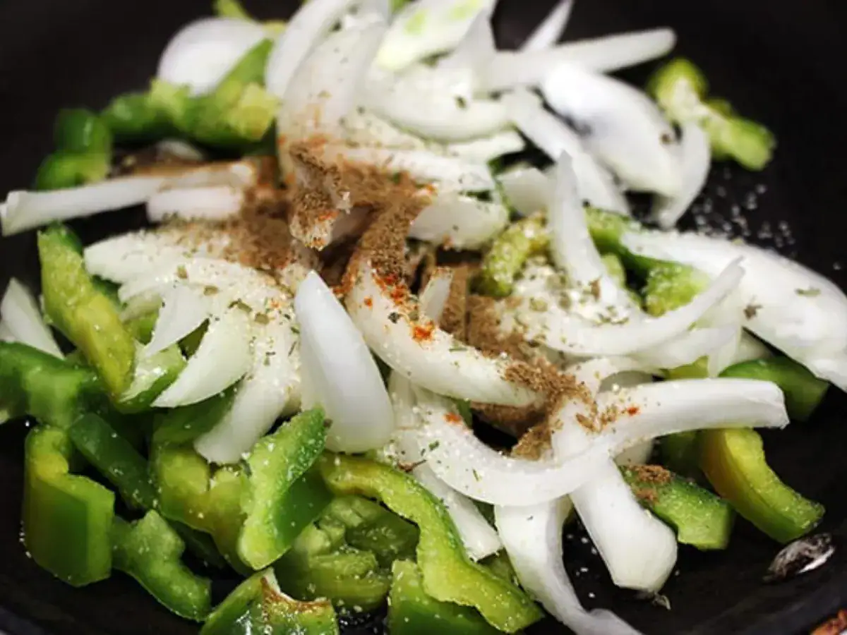 uncooked onions and peppers with seasoning on top