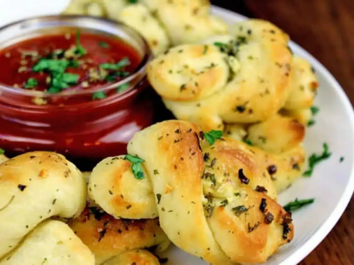 Twisted bread with garlic and herb garnish, served with red dipping sauce