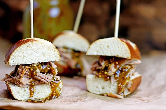 Tender Pulled Pork covered in a homemade raspberry honey mustard sauce with whole mustard seeds served in a toasted pretzel roll. Perfect for your tailgate or gameday party.