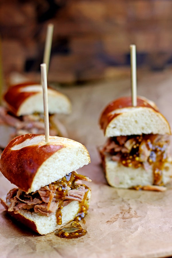 Tender Pulled Pork covered in a homemade raspberry honey mustard sauce with whole mustard seeds served in a toasted pretzel roll. Perfect for your tailgate or gameday party.