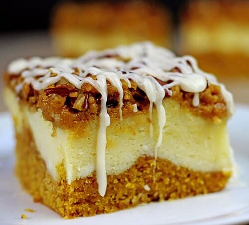 Layered pumpkin cheesecake bars topped with icing.