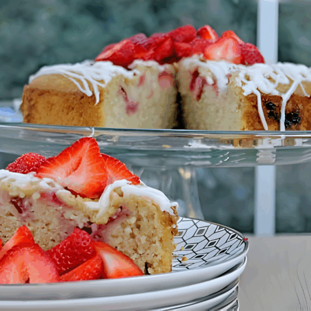 a fruity and nutty cake on top of a platter with a slice on top of a stack of plates