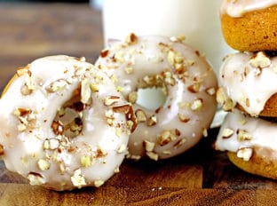 Baked Mini Pumpkin Donuts with Maple Icing. Tender Pumpkin baked donuts that are made in one bowl and bake in 8 minutes are covered in a quick two ingredient maple icing and finally are topped with crunchy pecans. It will look like you're a pro in the kitchen but these are a cinch to make!