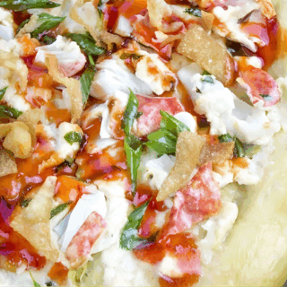seafood meat, dairy, wonton chips, and veggies on cooked dough
