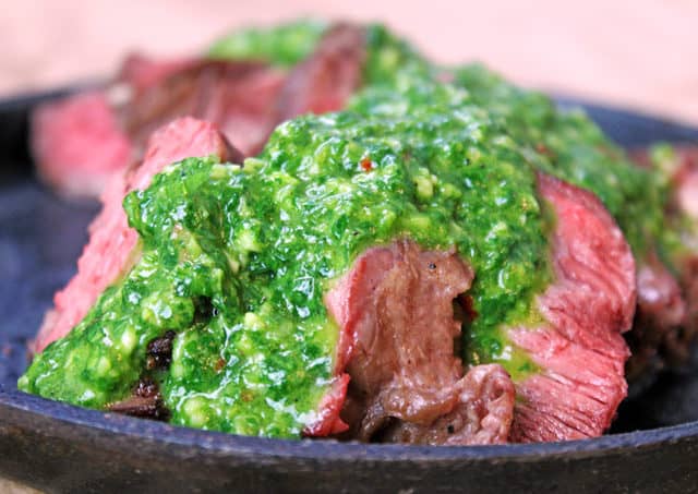 side view of plate with sliced steak and chimichurri sauce