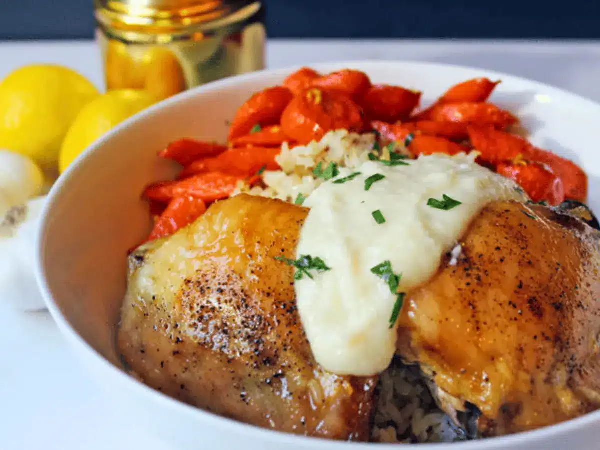 Bowl of cooked chicken thighs with veggies and garlic sauce