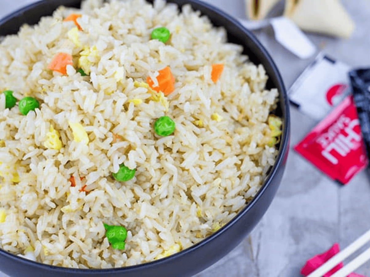 bowl of fried rice seasoned with soy sauce and vegetables. With chopsticks and soy sauce packages next to it.