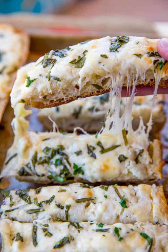 Spinach Artichoke Dip Cheesy Bread is two of your favorite appetizers in one. Cheesy garlic bread meets spinach and artichoke dip in just 30 minutes!