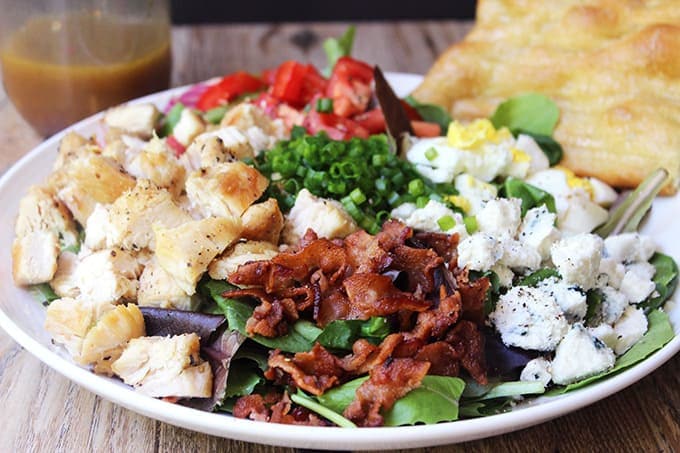 Salad with chicken, bacon, and cheese assembled on a plate