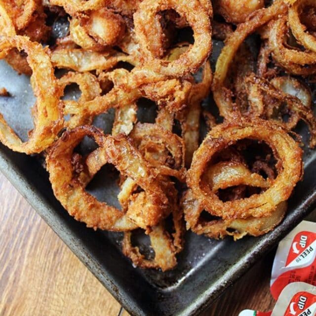 Onion rings on a platter with sauce on the side