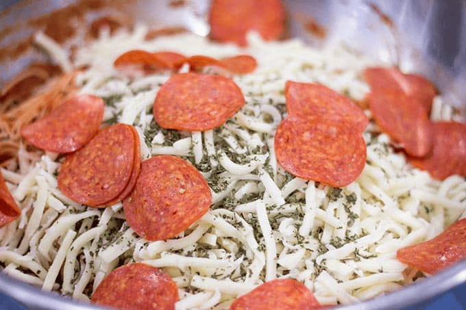 Pepperoni, cheese, and seasoning in a bowl