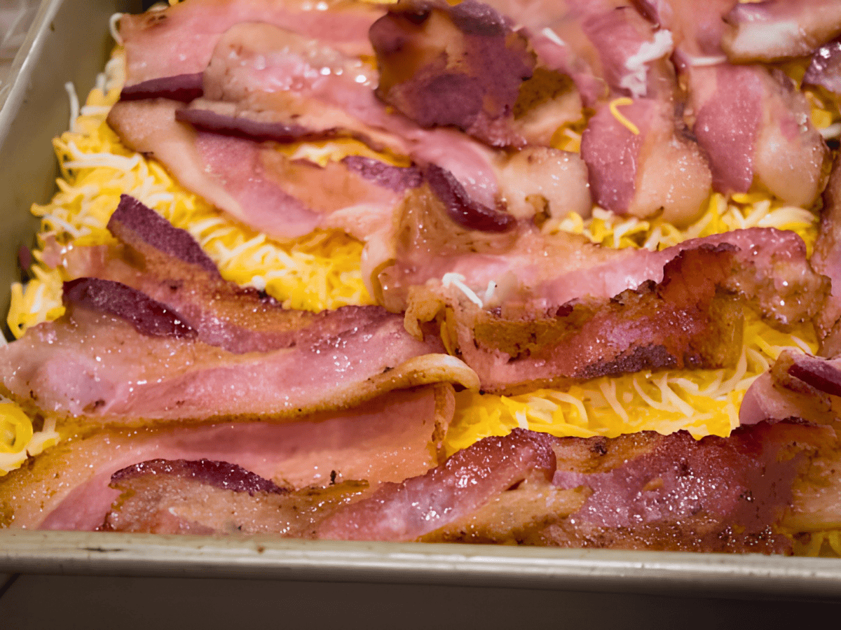 bacon on a bed of egg and cheese in a baking pan