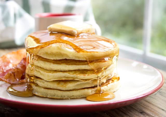 Stack of pancakes topped with butter and syrup.