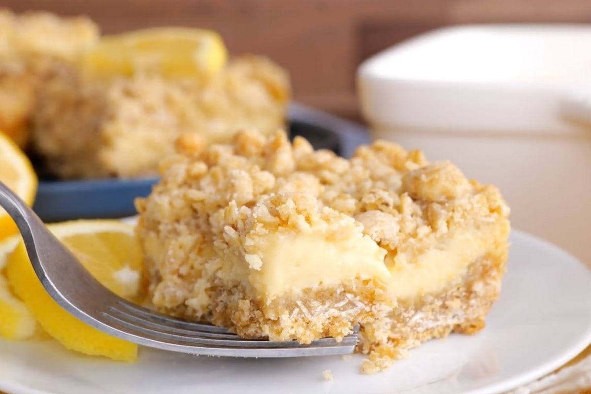 Creamy Lemon Crumb Bars slice on plate with lemon wedges and fork