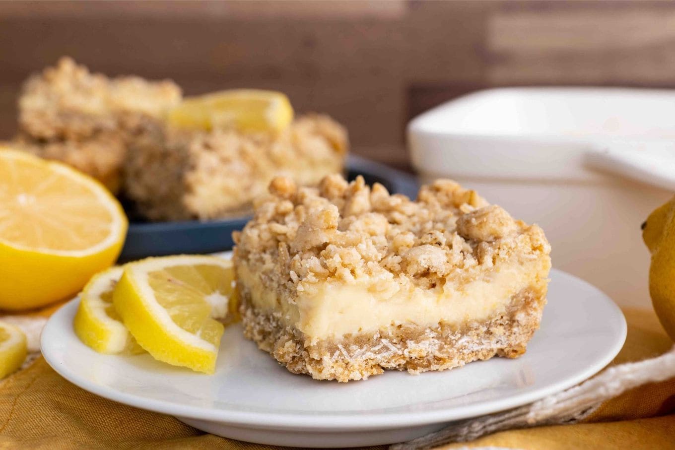 Creamy Lemon Crumb Bars slice on plate with lemon wedges