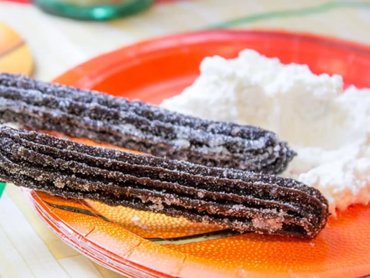 2 churros on an orange plate with whipped cream 