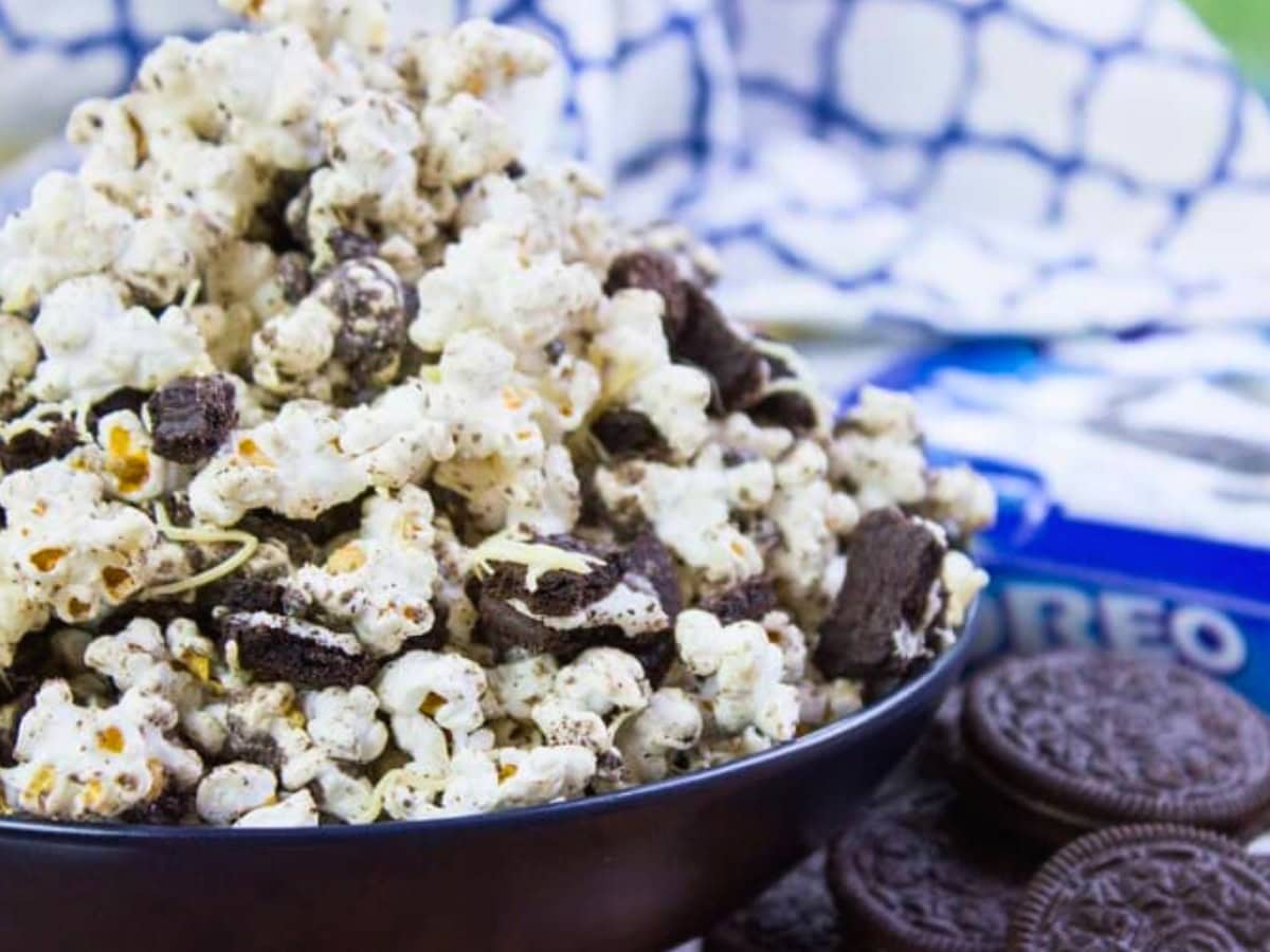 Sweet cookies and cream popcorn with Oreos on the side and dish towel in the background