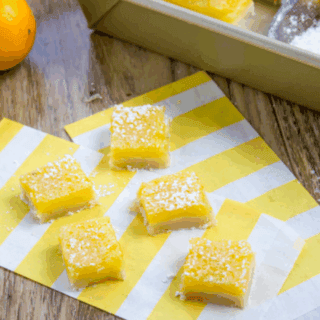 tangy sweet yellow squares with sugar on top on a striped napkin on table