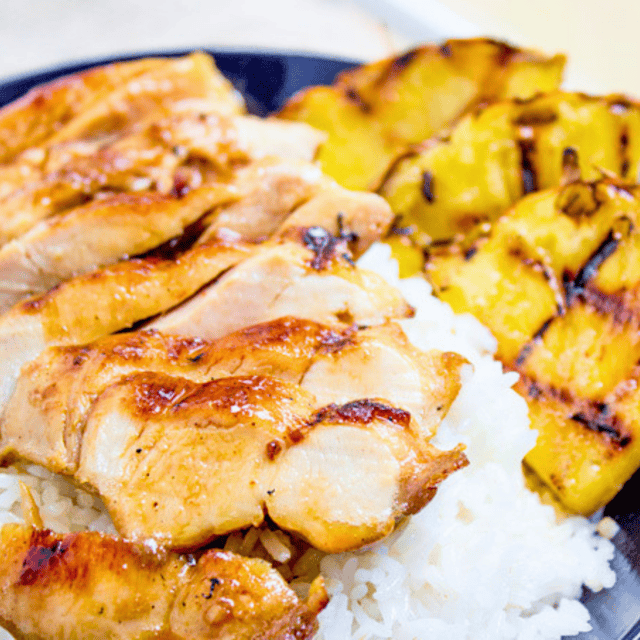 Cooked chicken slices plated with rice and pineapple.