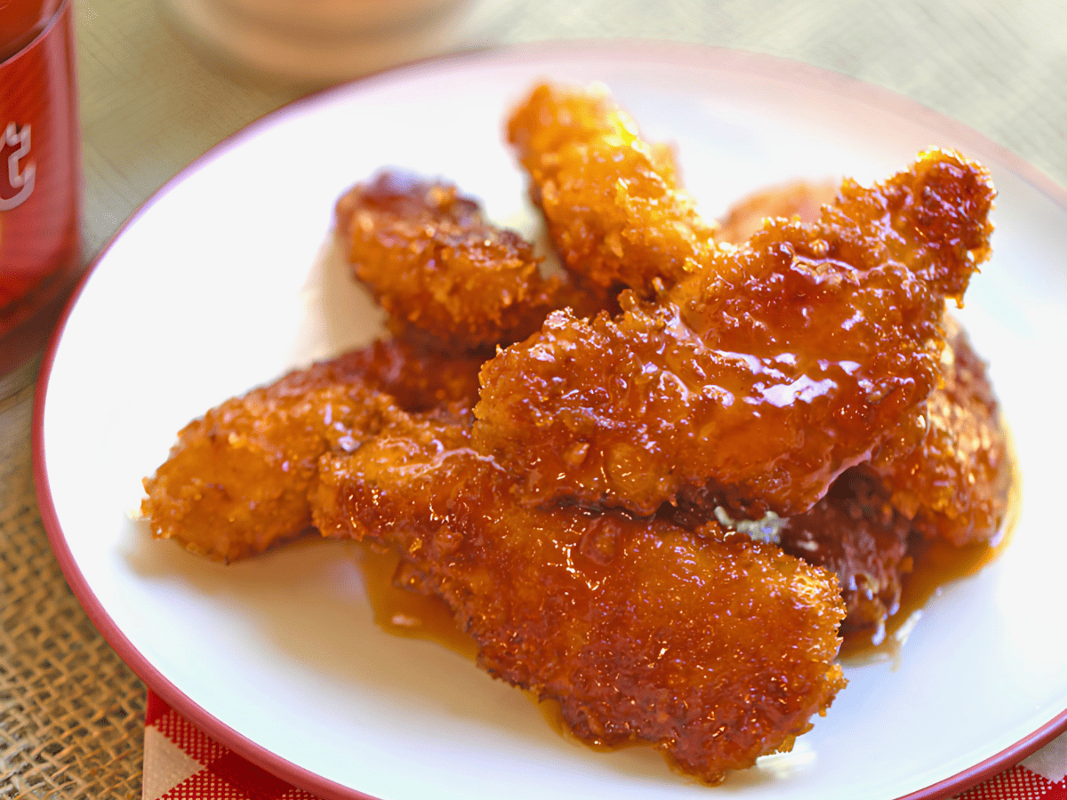 crispy sticky chicken strips on a white plate