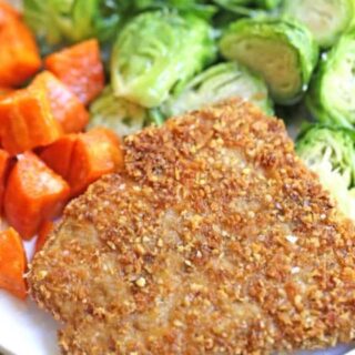 A piece of fish on a plate with brussel sprouts and sweet potatoes