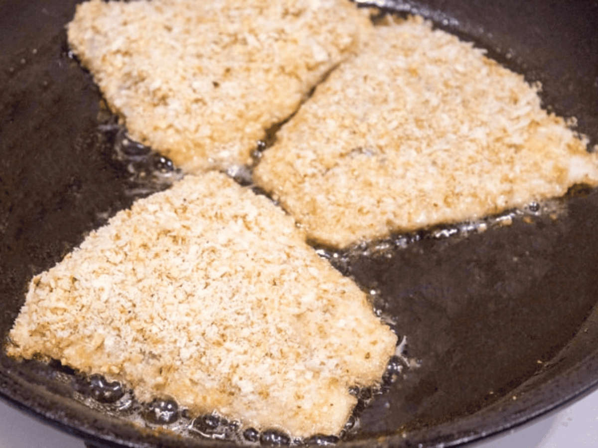 crusted fish cooking in a pan