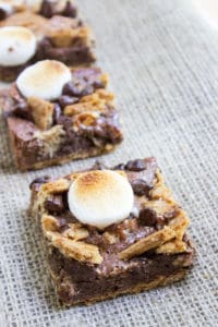 S'mores Brownies start with a graham cracker base and rich chocolate brownie. They're topped with buttery graham crackers, milk chocolate chips and toasted marshmallows for the perfect summery treat with no bonfire!
